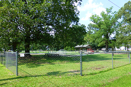View of the park, displaying the playground and picnic shelter within the border fence