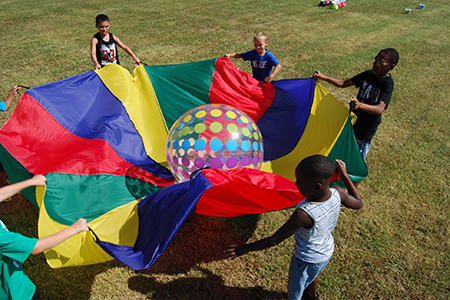 Children playing with beach ball and large tarp