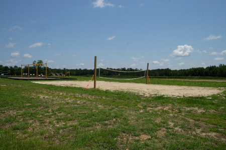 View of the volleyball court and a swing set behind the court